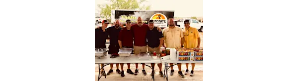 People at a cookout standing behind a table with food